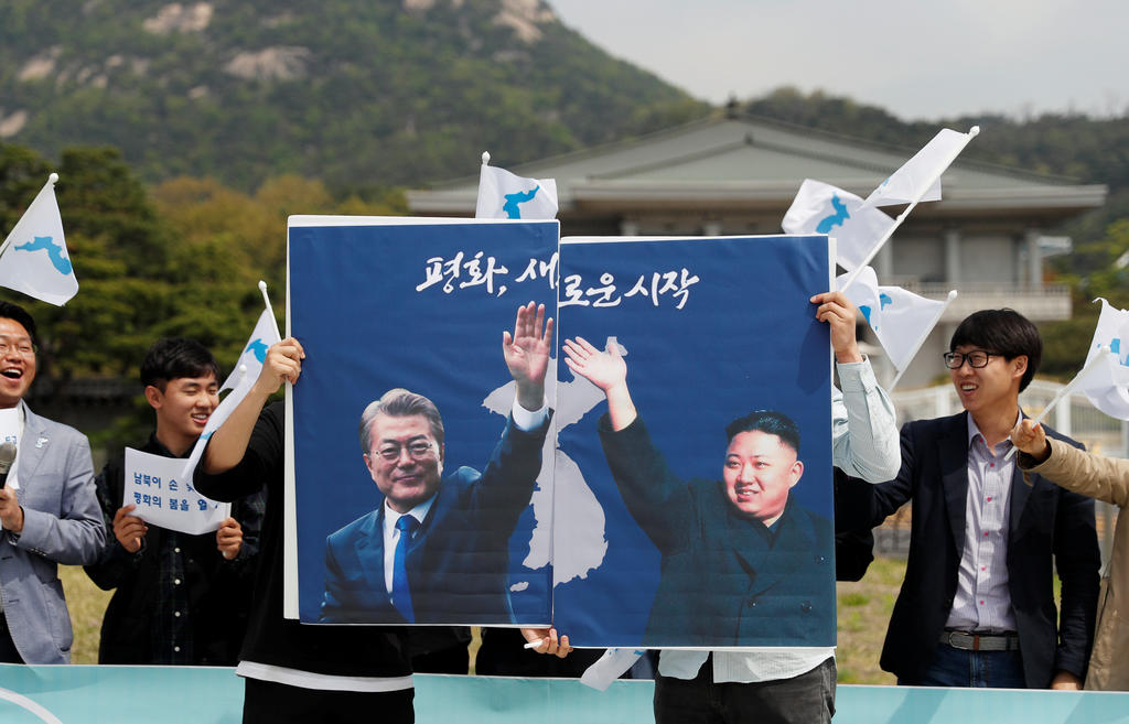 Students hold posters with pictures of South Korea's President Moon Jae-in and North Korea's leader Kim Jong Un during a pro-unification rally ahead of the upcoming summit between North and South Korea in Seoul